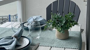 A balcony table set with plates, glasses, and a potted plant, overlooking a beach. - Oceanfront condo with private balcony and unobstructed views -Wildwood Crest (Wildwood Crest)