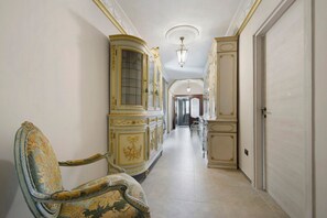 A hallway with ornate furniture, a chandelier, and a door. - Apartment in a Villa (Mosso Santa Maria)
