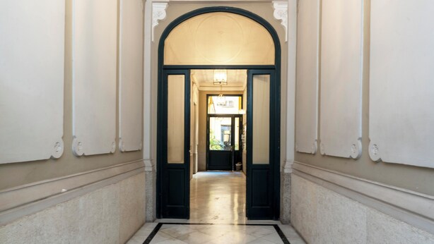 A hallway with a marble floor, white walls, and a dark door frame.
