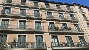 A multi-story building with balconies, shutters, and a classic architectural style.