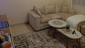 Ein Wohnzimmer mit einem beigefarbenen Sofa, einem runden Couchtisch und einem gemusterten Teppich.