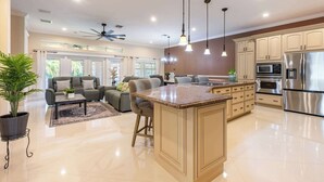 A modern kitchen with a central island, stainless steel appliances, and a ceiling fan. - ‼️3BR Getaway Near Everything •Fenced Yard • BBQ (West Palm Beach)