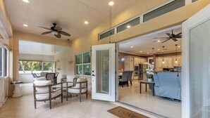 A spacious living area with a seating arrangement, a sliding glass door leading to a kitchen, and a ceiling fan. - ‼️3BR Getaway Near Everything •Fenced Yard • BBQ (West Palm Beach)