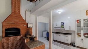A kitchen with a brick oven, white cabinets, and a tiled backsplash.