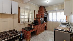 A kitchen with a brick oven, tiled walls, a gas stove, and a sink. - Ch Cara com Churrasqueira sal o de Jogos e Wi-fi (Suzano)