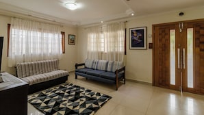 A living room with a sofa, a patterned rug, and a wooden door. - Ch Cara com Churrasqueira sal o de Jogos e Wi-fi (Suzano)
