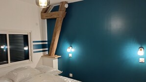 Un dormitorio con cama, una escalera de madera y luces fijadas a la pared.