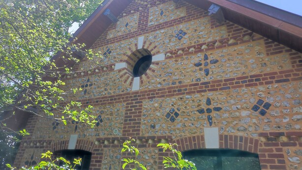 Un edificio con una fachada de ladrillo distintiva que presenta un mosaico de formas y tamaños diversos.