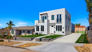 A modern two-story house with a flat roof, large windows, and a well-maintained lawn. - Airy Ocean Beach Home with Coastal Views (San Diego)
