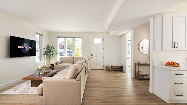 A spacious living room with a sofa, a coffee table, and a TV mounted on the wall. - Airy Ocean Beach Home with Coastal Views (San Diego)