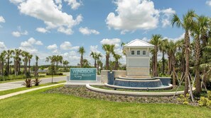 A resort sign with a pool and palm trees.