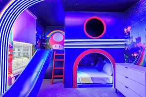 Une salle de jeux pour enfants avec un toboggan, une échelle, un lit et une commode.