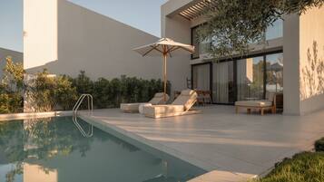 Un espace piscine extérieur moderne, doté de chaises longues, d’une terrasse en bois et d’une pergola.