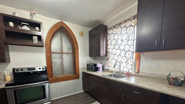 Una cocina con armarios de madera, horno doble, microondas y lavabo.