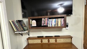 Una sala de estar con un televisor de pantalla plana montado sobre un mueble de madera con estantería integrada.