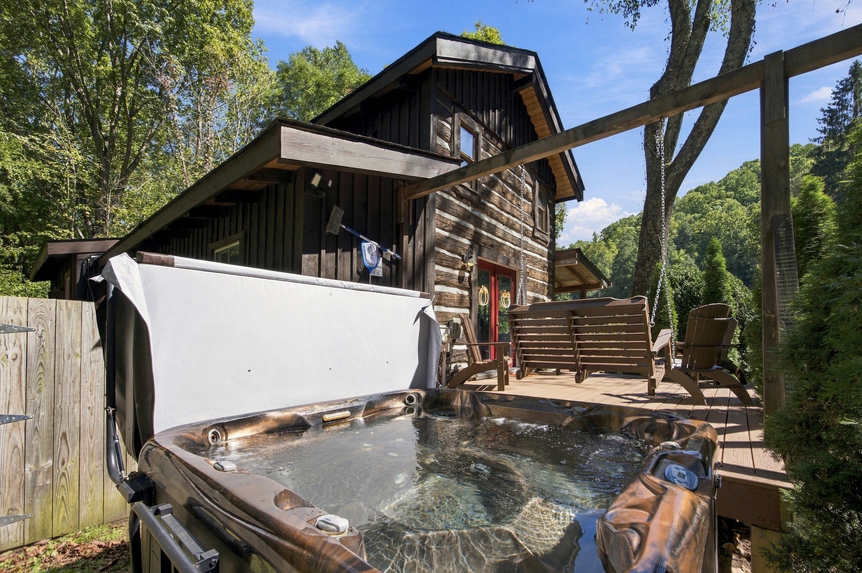 Eine rustikale Holzhütte mit Whirlpool und Sitzgelegenheiten im Freien.