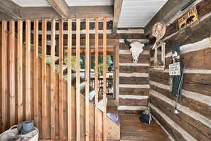Interior rústico de una cabaña con una escalera de madera, una decoración de cráneo de vaca y un letrero que dice 'No acariciar'.