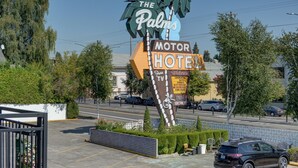 A sign for The Palm's Motor Hotel with palm trees and a welcome message. - The Palms Motel (Portland)