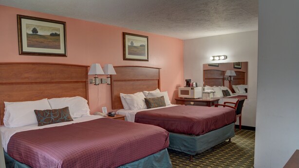 A hotel room with two beds, a desk, a chair, a microwave, and a nightstand. - The Palms Motel (Portland)