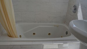 A bathroom with a bathtub, a sink, and marble tiles. - The Palms Motel (Portland)