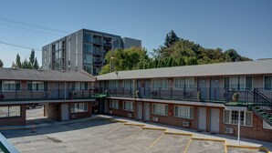 A motel with a parking lot, a covered outdoor area, and a building with multiple floors and balconies. - The Palms Motel (Portland)