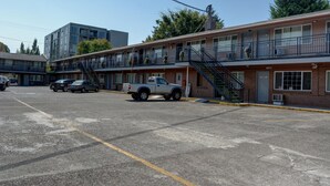 A motel with multiple floors, outdoor parking, and a staircase leading to the upper levels. - The Palms Motel (Portland)
