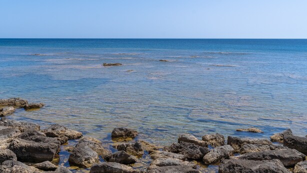 Blick auf die Küste mit klarem Wasser und felsigem Ufer.