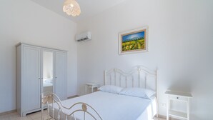 A bedroom with a bed, a wardrobe, a nightstand, and a painting on the wall. - Apartment 'Terrazza Sul Mare' with Sea View, Wi-Fi and Air Conditioning (Marzamemi)