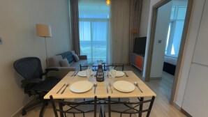 A dining area with a table set for four, a sofa, a TV, and a view of the outdoors.