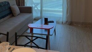 A modern living room with a sofa, a small table, and a dining area.