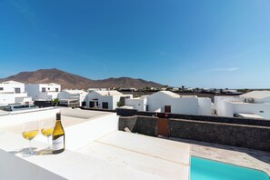 A rooftop terrace with a pool, white buildings, and a mountain in the background. - Ereza Villas La Granja (Yaiza)