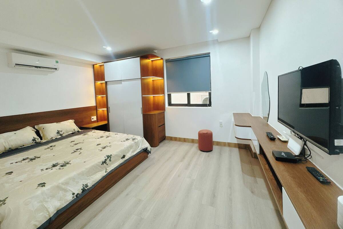 Une chambre d’hôtel moderne équipée d’un lit, d’un bureau, d’une télévision et d’une fenêtre donnant sur un paysage agréable.