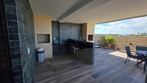 A modern kitchen with a black countertop and a view of the city. - Flat Centro Porto de Galinhas 204 byLP (Ipojuca)