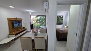 A modern hotel room with a dining area, a bed, and a TV. - Flat Centro Porto de Galinhas 204 byLP (Ipojuca)