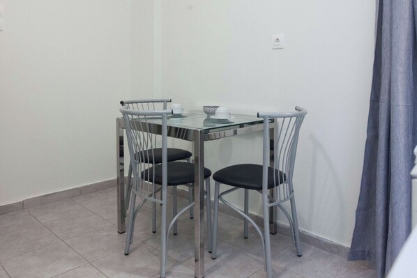 Un pequeño comedor moderno con una mesa de vidrio y cuatro sillas de metal.