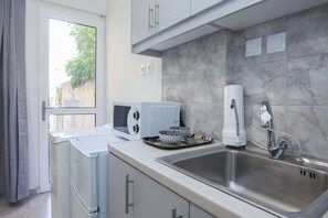 Cocina moderna con pileta de acero inoxidable, electrodomésticos blancos y vista a zonas verdes.