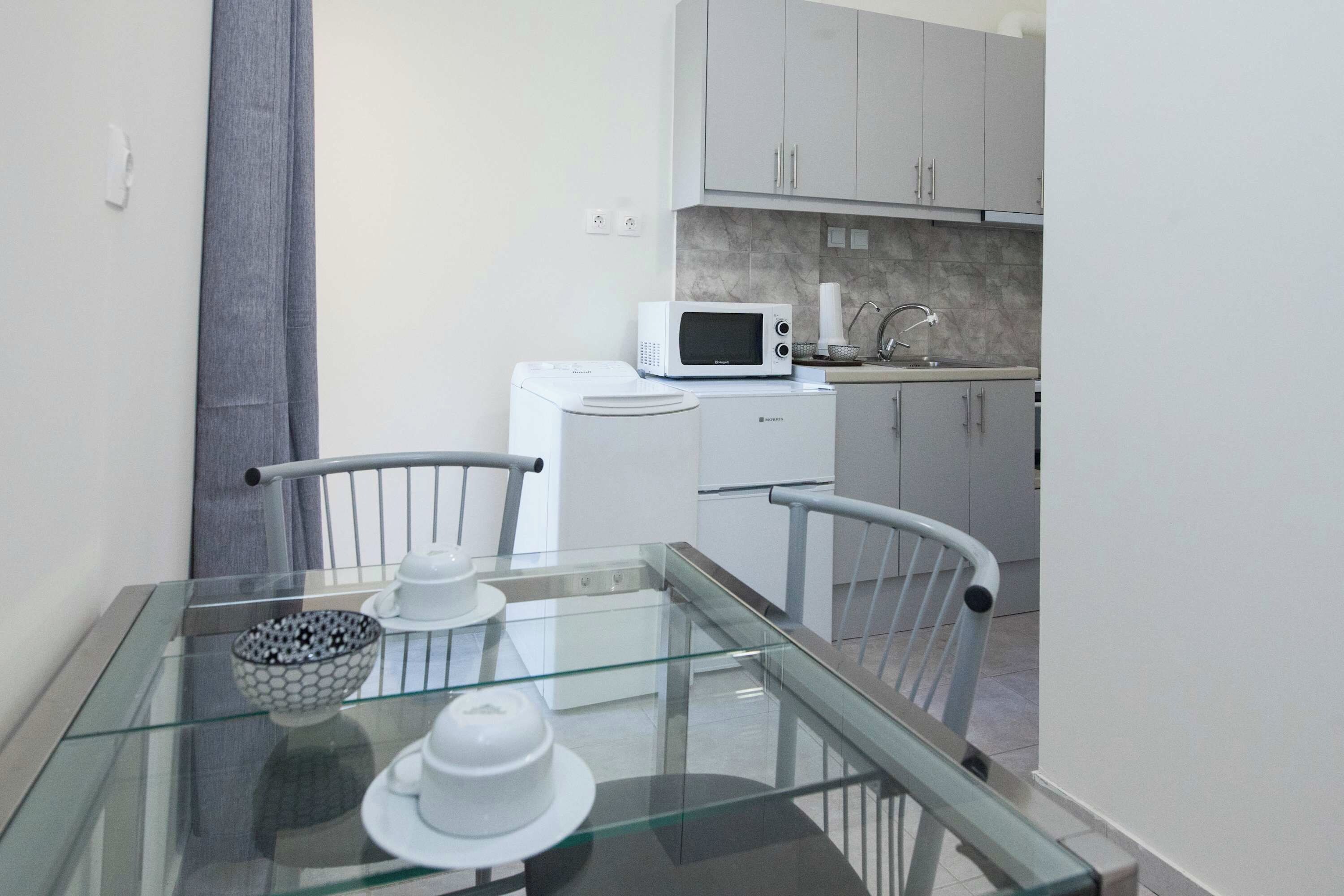 A modern kitchen with a microwave, a small refrigerator, and a sink.