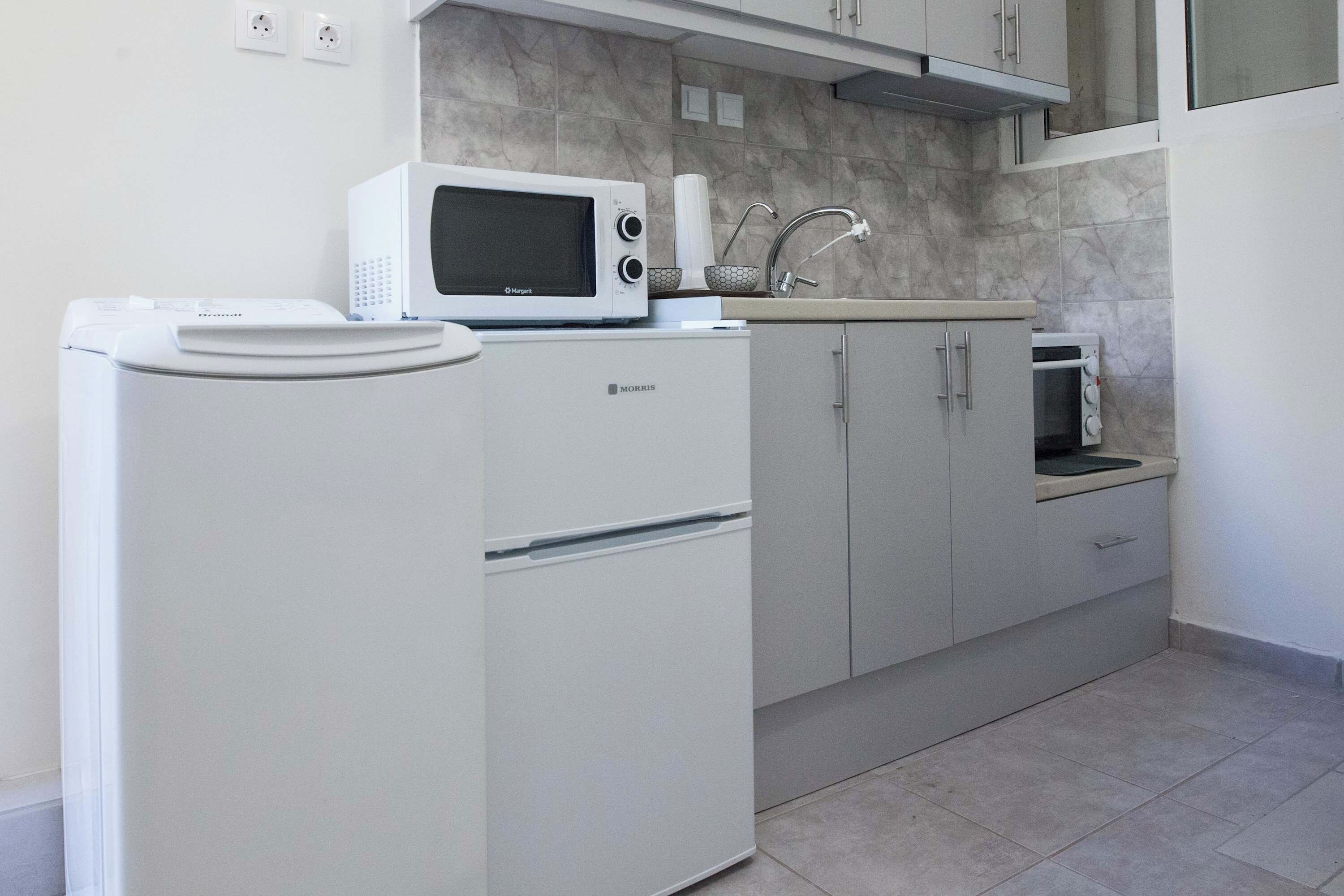 A compact kitchen with a refrigerator, microwave, and a small oven.