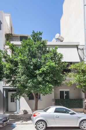 A residential building with a tree in front, a parked car, and a clear blue sky. - Sunny 1 Bd Apt in Kallithea with Patio (Kallithea)