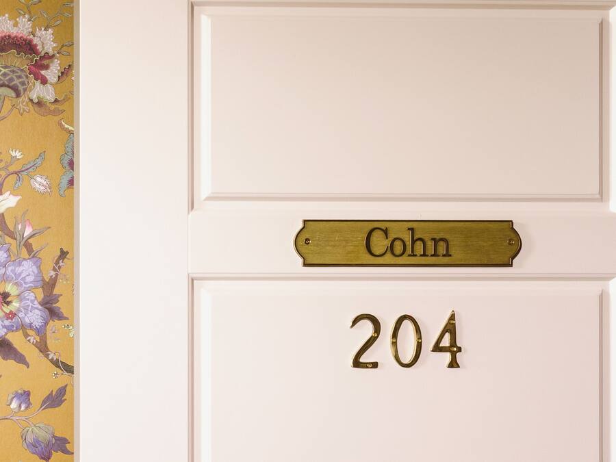 Ovi, jossa on messinkinen nimikyltti, jossa lukee ”Cohn”, ja messinkinen numero ”204” valkoisessa ovilevyssä.