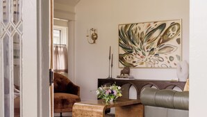 Una stanza con un lampadario, un divano, un tavolino da caffè e un quadro appeso al muro.