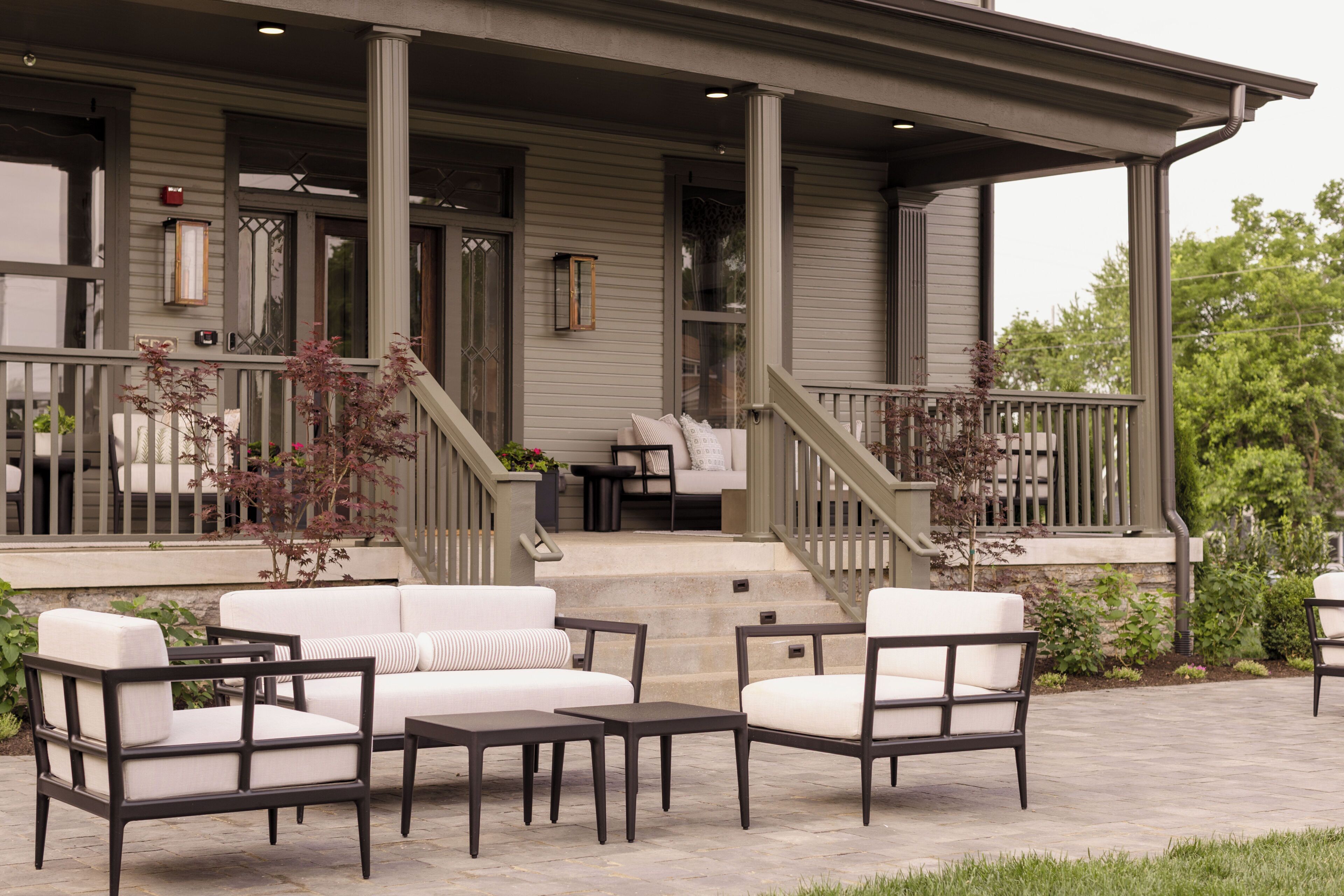 A covered porch with outdoor furniture, a staircase, and a view of the house.