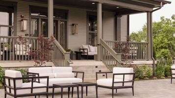 A covered porch with outdoor furniture, a staircase, and a view of the house.