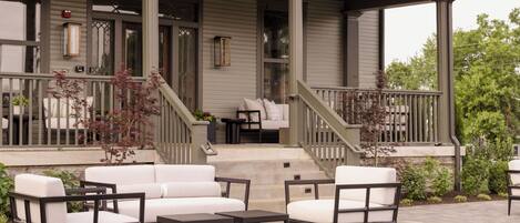 A covered porch with outdoor furniture, a staircase, and a view of the house.