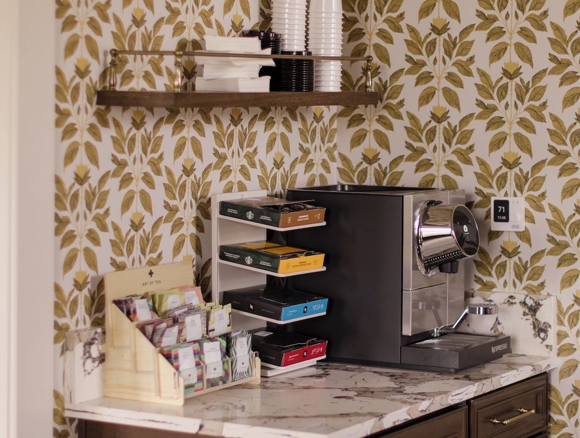 A coffee machine with a drip tray, a shelf with coffee pods, and a sign with the number 71.