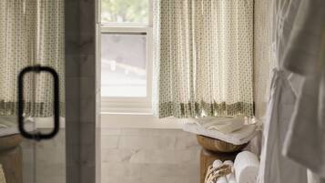 A bathroom with a window, a towel rack, and a wooden stool with towels.