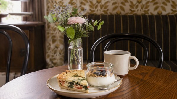 A table with a slice of quiche, a glass of yogurt with berries, and a cup of coffee. - Sylvan Park Boarding House (Nashville)
