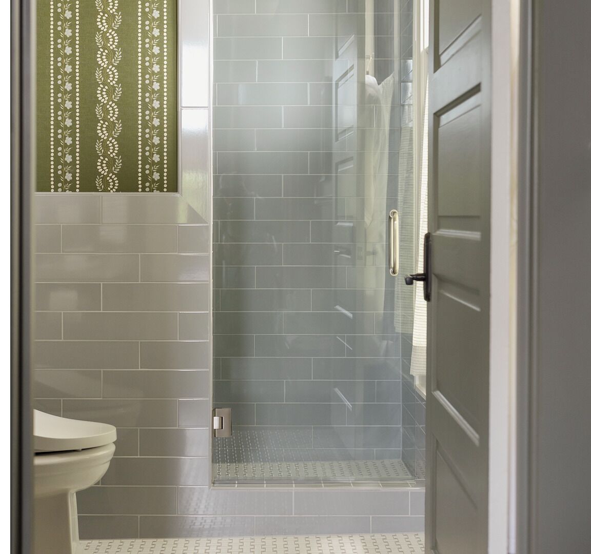 Een badkamer met een douche, toilet en een deur.
