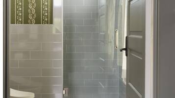 Een badkamer met een douche, toilet en een deur.