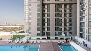A modern high-rise building with a rooftop pool and lounge area.